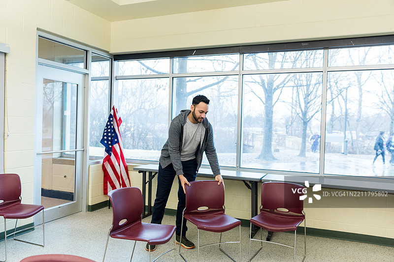 年轻男子在教室里整理椅子图片素材