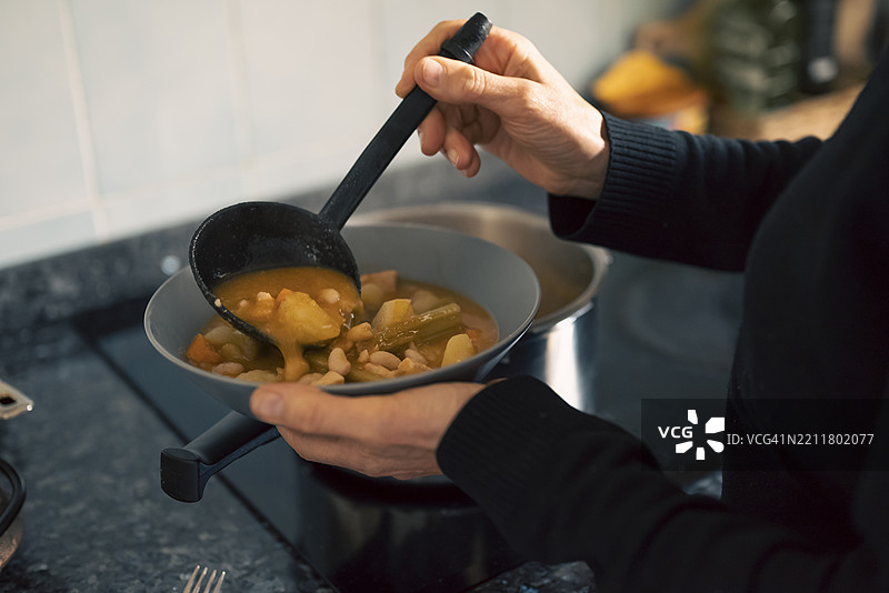 母亲在家厨房为家庭餐准备自制豆子炖菜，健康食品，家庭食谱图片素材