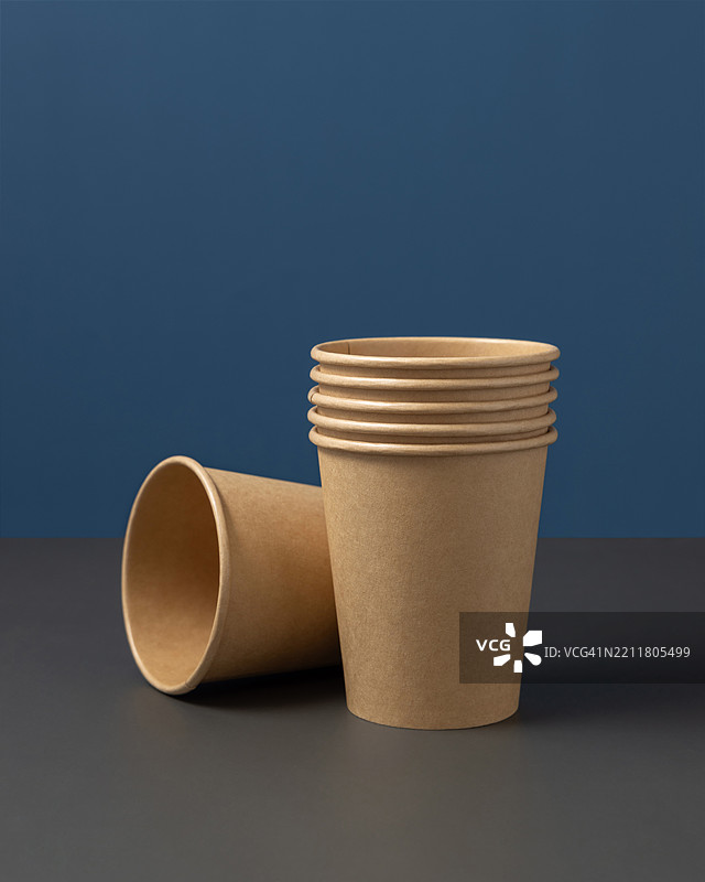 灰色背景下的蓝色近景，一次性米色纸杯，展示无塑料生活方式的样式图片素材