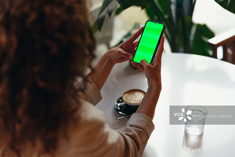女商人在咖啡馆使用带绿幕的智能手机图片素材