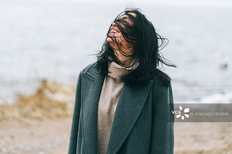 快乐的韩国女性在寒冷的海滩上享受海风和潮汐图片素材