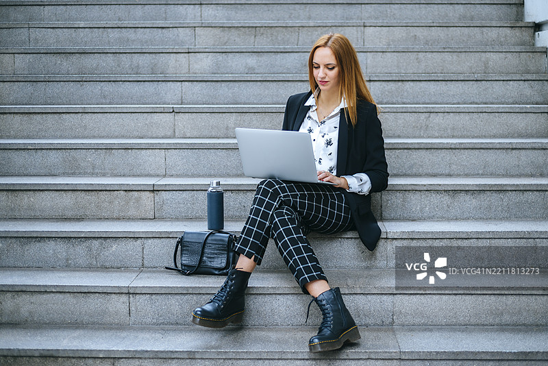在户外台阶上工作的女商人使用笔记本电脑图片素材