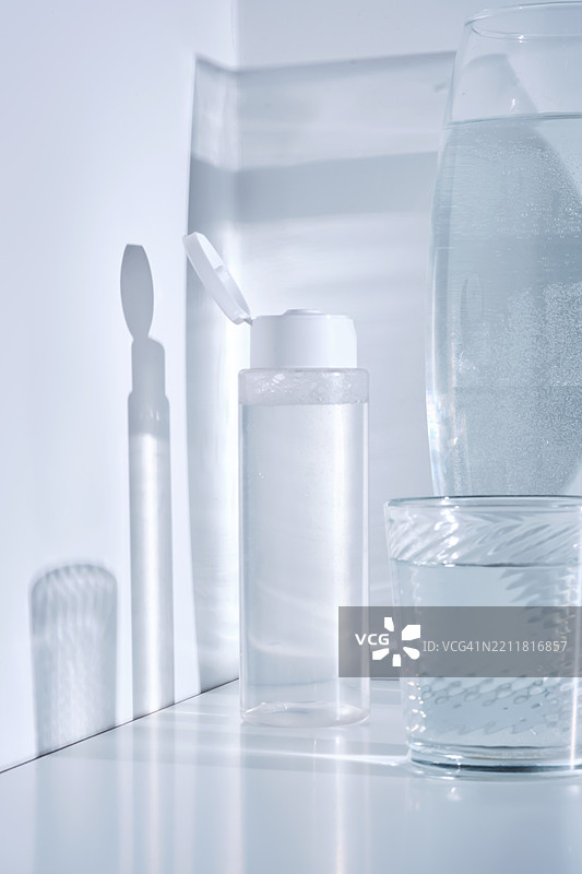 白色背景上带有水面倒影的化妆品护肤产品瓶子图片素材