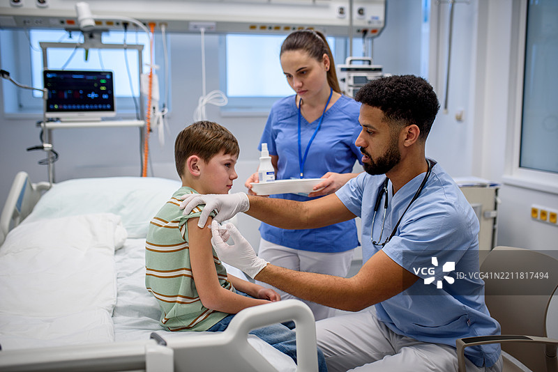 医生在儿童免疫接种期间给小男孩接种疫苗。图片素材