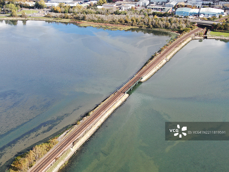 从高空俯瞰铁路穿过普尔港一片静水的浅水域，沿着堤道延伸。图片素材
