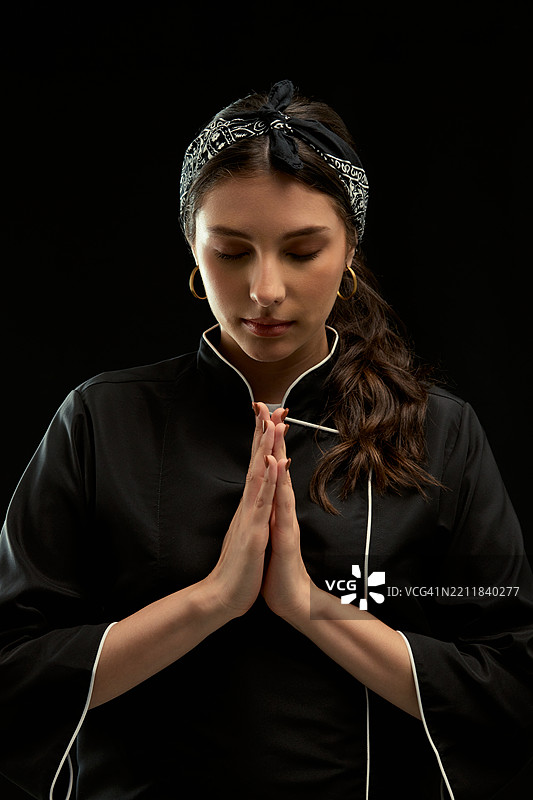 面带敬意的女厨师，双手合十，表示尊重图片素材