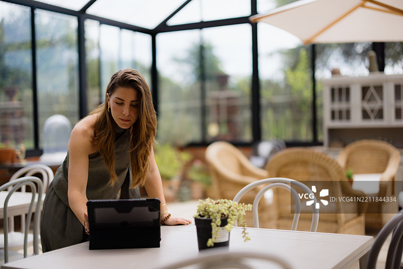 年轻女性在温室餐厅使用平板电脑图片素材