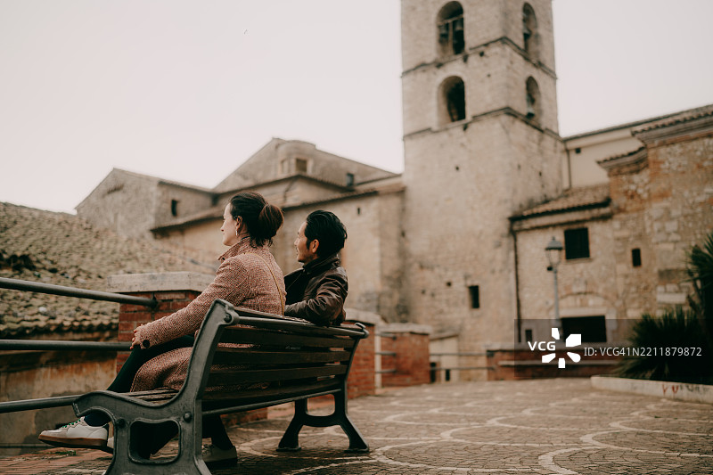 在拉齐奥的维罗利意大利山顶村庄里，一对情侣坐在长椅上。图片素材