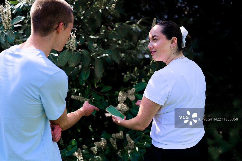 兄妹俩用智能手机讨论花卉图片素材