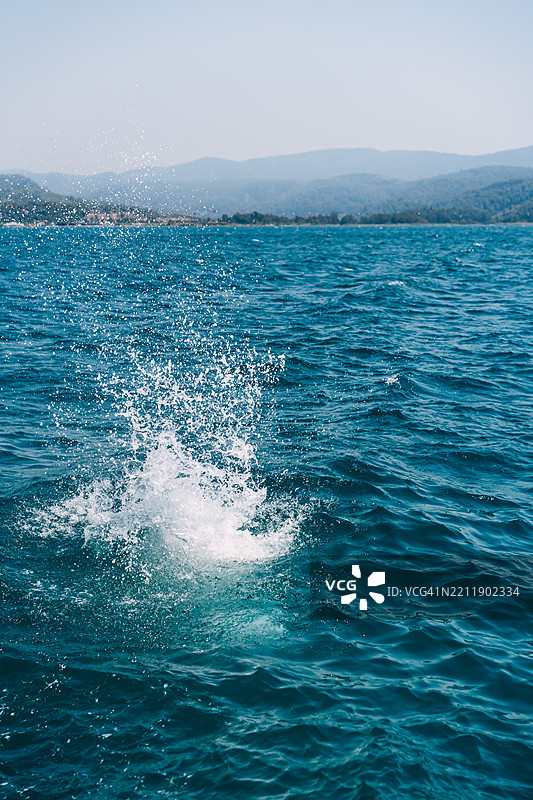 跳跃的男人在海中溅起水花。图片素材