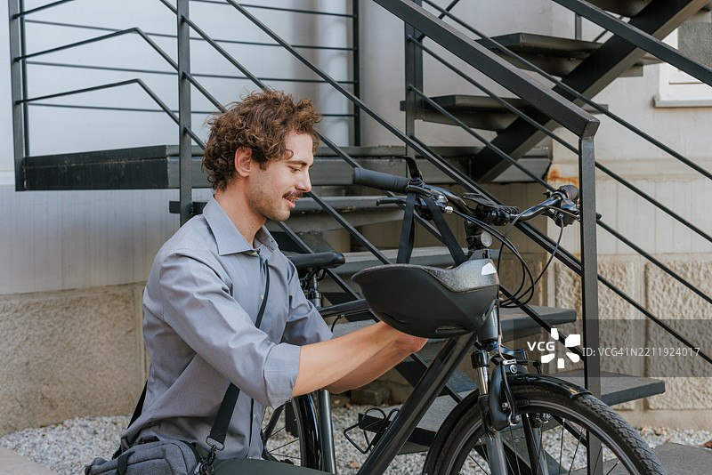 男子在户外的楼梯旁锁好他的自行车图片素材