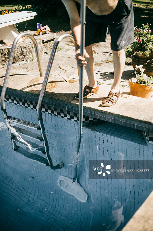 一个无法辨认的人正在用泳池网清洁泳池图片素材
