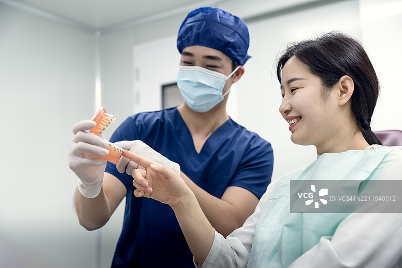 牙医在诊所展示牙齿模型。图片素材