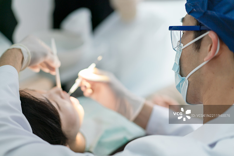 牙医在牙科诊所为年轻女性治疗牙齿图片素材