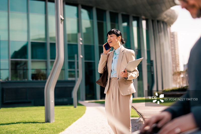 女商人在办公楼外走动并打电话图片素材