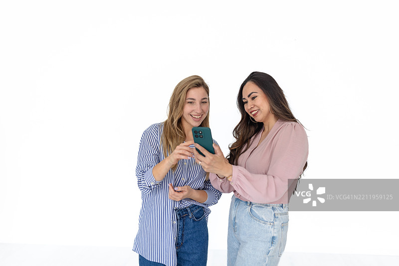 女性在白色背景下微笑着使用智能手机上的移动应用程序图片素材