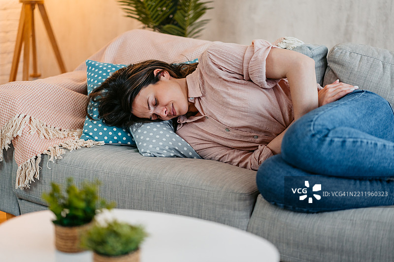 年轻女性在家中经历经期疼痛图片素材