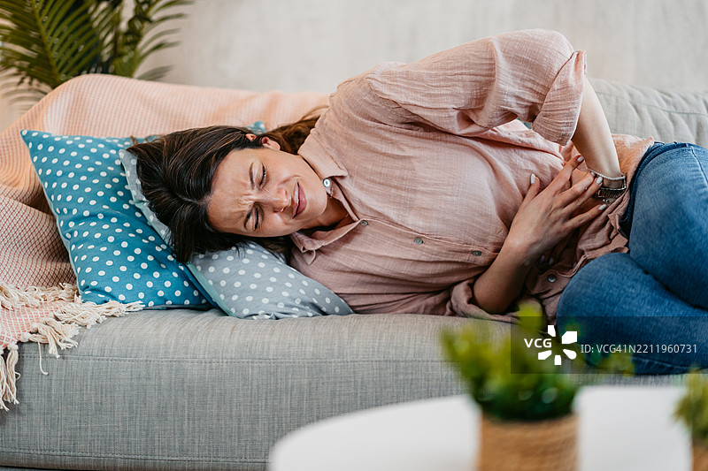 年轻女性在家中经历经期疼痛图片素材
