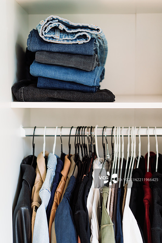 整齐的衣柜，叠放的牛仔裤和挂着的各种衣物图片素材