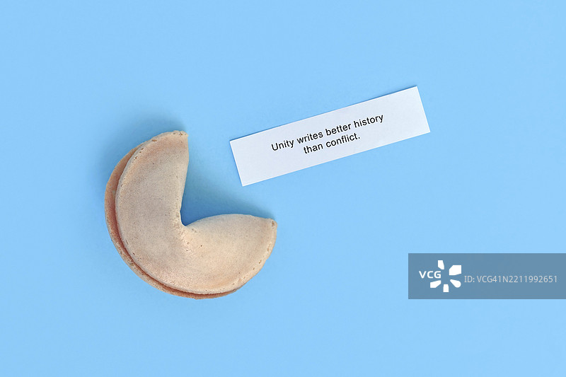 写着“团结比冲突更能书写历史”的幸运饼干，背景为蓝色图片素材