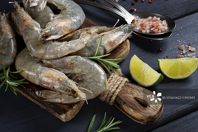 新鲜生的白脚虾和瓦氏虾，放在木砧板上，旁边有青柠片和调料图片素材