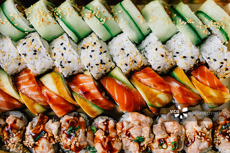 各种色彩鲜艳的新鲜寿司卷，配有三文鱼、金枪鱼和鳄梨，顶部装饰丰富图片素材