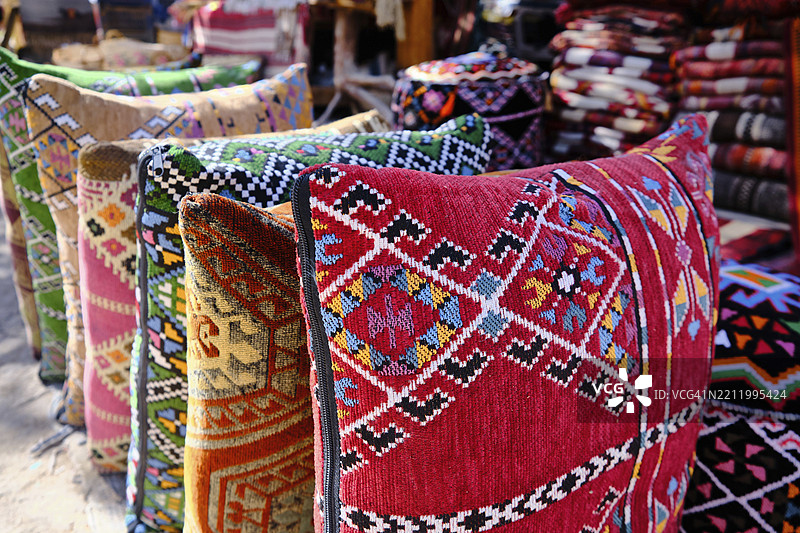 中东集市上传统的多彩柏柏尔手工编织羊毛枕套和地毯。传统集市上具有几何图案的柏柏尔工艺品。图片素材