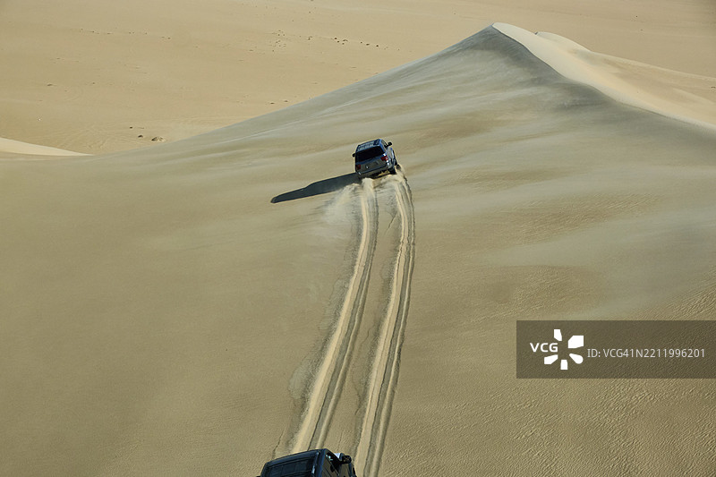 沙漠越野探险。SUV汽车在撒哈拉沙漠的沙丘上飞驰图片素材