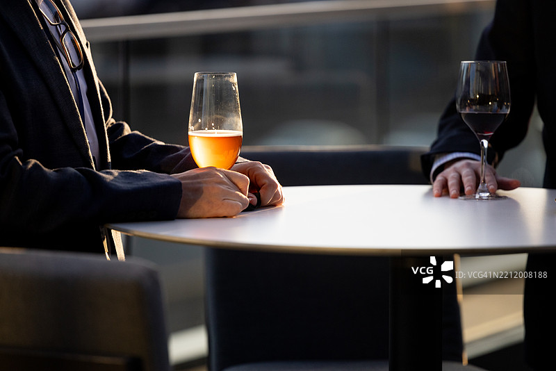 两名男子在日落时分的户外桌子上喝酒图片素材