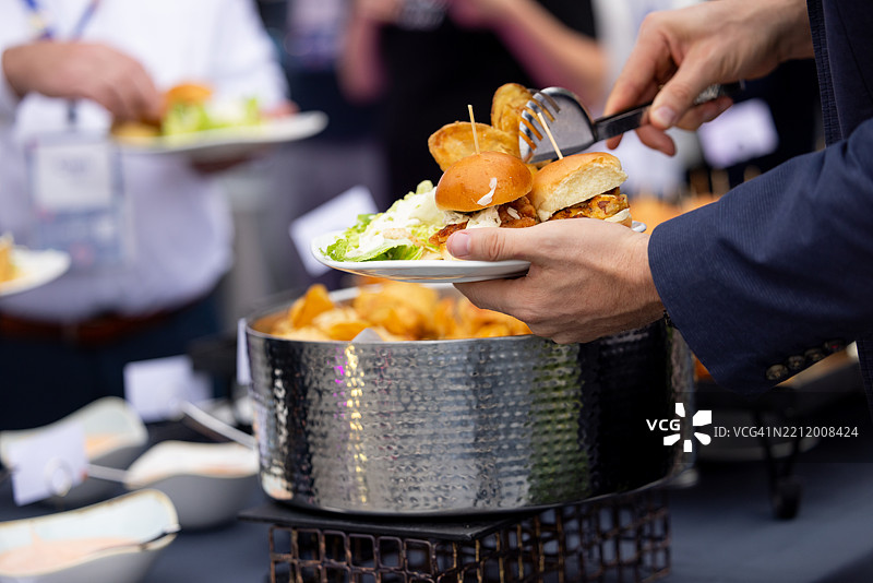 客人自助取迷你汉堡和薯片在自助餐台图片素材