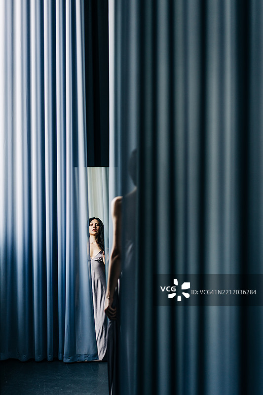 一位穿着裙子的美丽女性在轻盈的布料中照镜子。图片素材