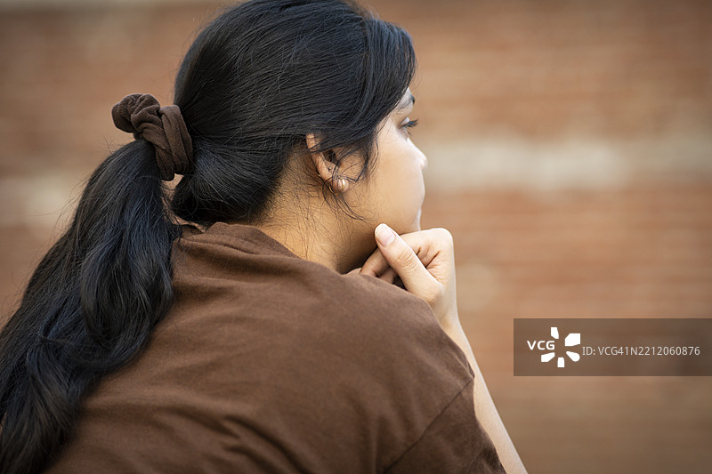 年轻女子在阳台上沉思，面露空洞的表情。图片素材