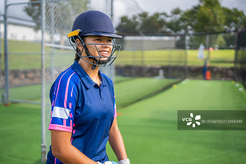 微笑的女青少年板球运动员戴着击球头盔图片素材