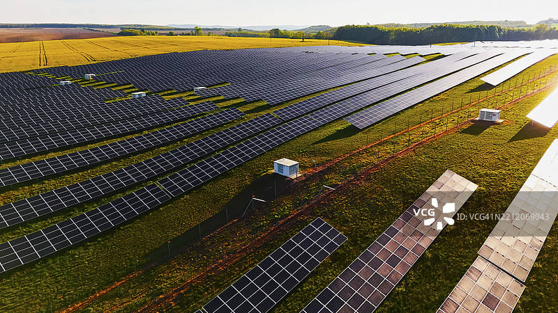 广阔的太阳能发电厂位于明亮的农业田野中，配备现代化的面板图片素材