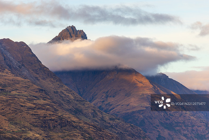 云彩环绕着山峰，沐浴在午后的阳光中图片素材