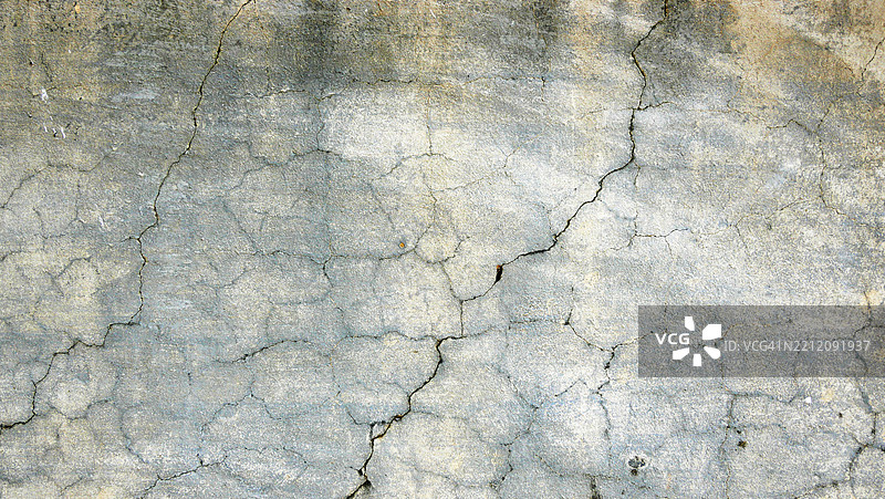 裂纹和纹理的混凝土墙，涂成灰色、黄色和白色，经过风化。图片素材