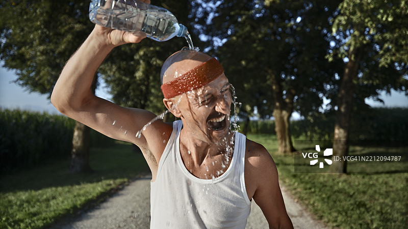 中年男子在阳光明媚的日子里穿着复古服装，用水瓶降温图片素材