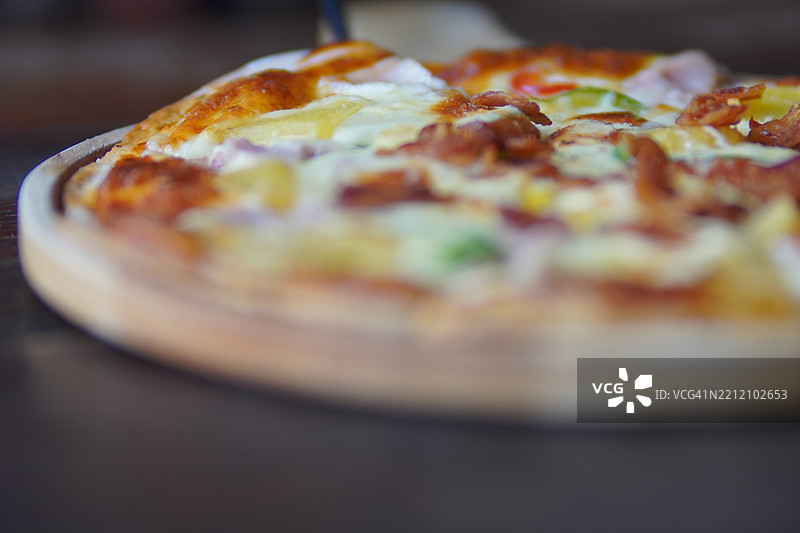 木托盘上的夏威夷披萨，上面有火腿、培根、菠萝和披萨酱奶酪，背景为美食场景图片素材