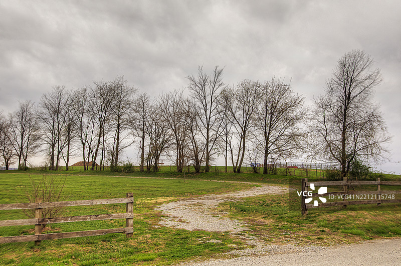 弯曲的土路蜿蜒穿过阴云密布的乡村风光图片素材