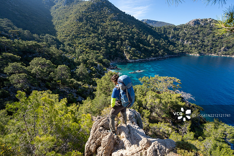 背包客在费特希耶的卡巴克湾附近的森林中，欣赏着美丽的隐秘海盗湾，沿着吕基亚小道。图片素材