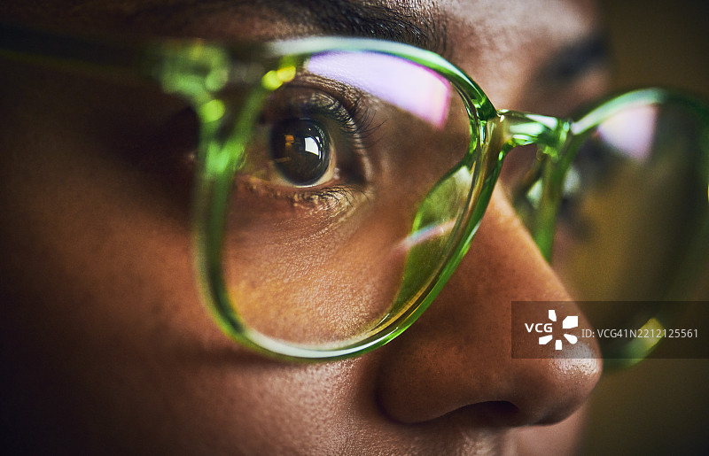 专注的女性在深夜佩戴绿色眼镜图片素材