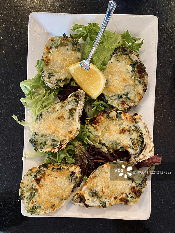 洛克菲勒生蚝配绿叶蔬菜和柠檬图片素材