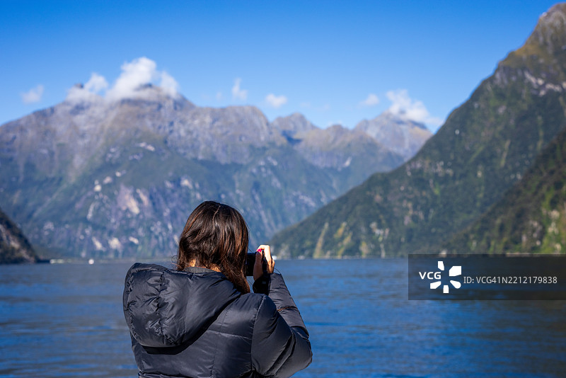 年轻女性在米尔福德峡湾拍照图片素材
