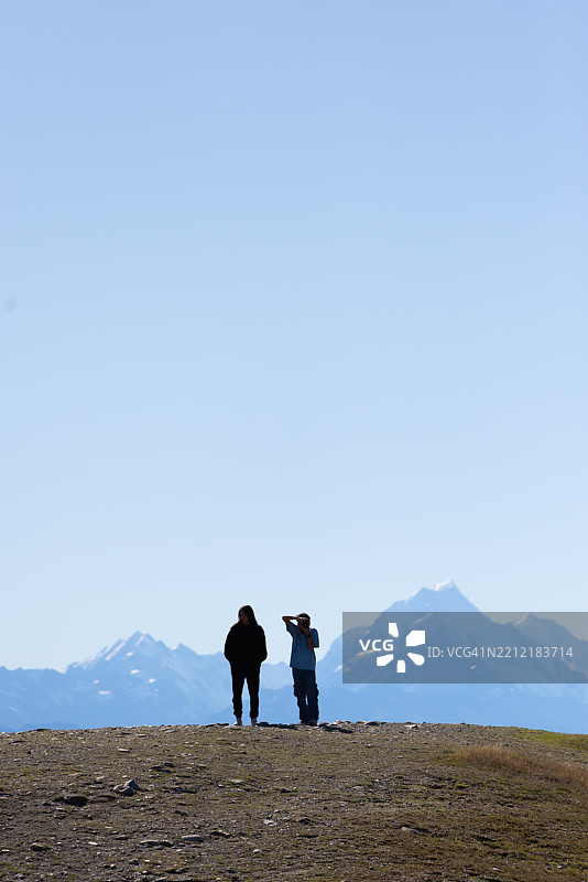 兄弟姐妹站在山顶，眺望库克山（Aoraki）峰。图片素材