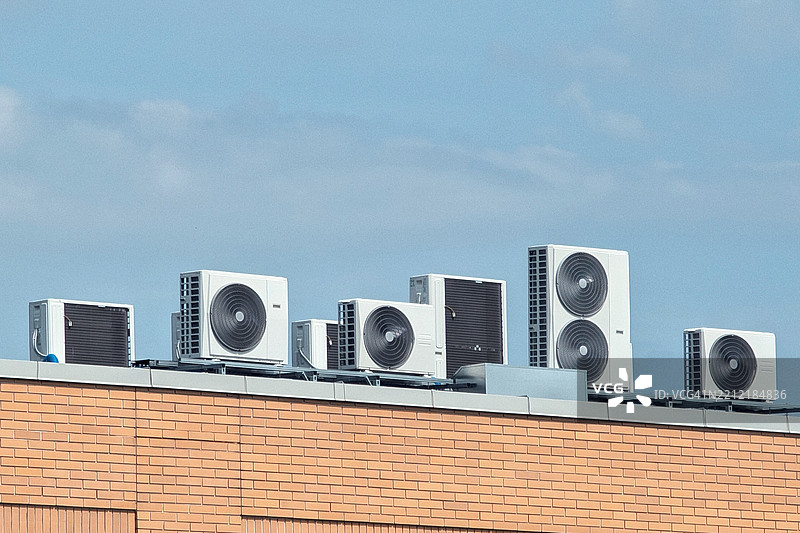 建筑物屋顶的空调设备在蓝天背景下进行气候控制图片素材