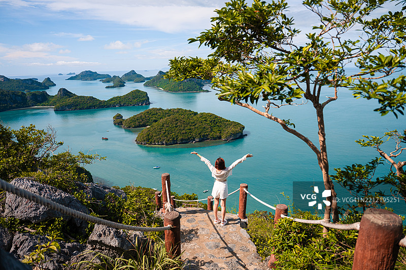 在泰国的安通群岛，一位年轻女性站着凝视着岩石，享受着明亮的时刻。图片素材