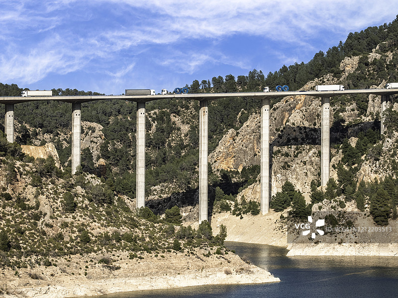 高速公路上重型卡车在跨越水库的高架桥上行驶。图片素材