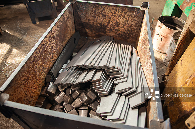 工业金属箱中堆放的切割钢件在制造车间图片素材