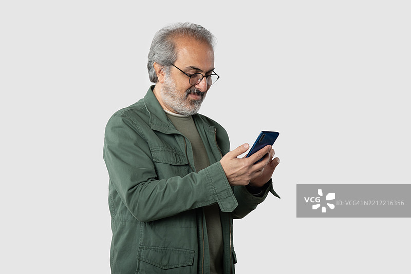 留着胡子的男人肖像，手持智能手机。图片素材