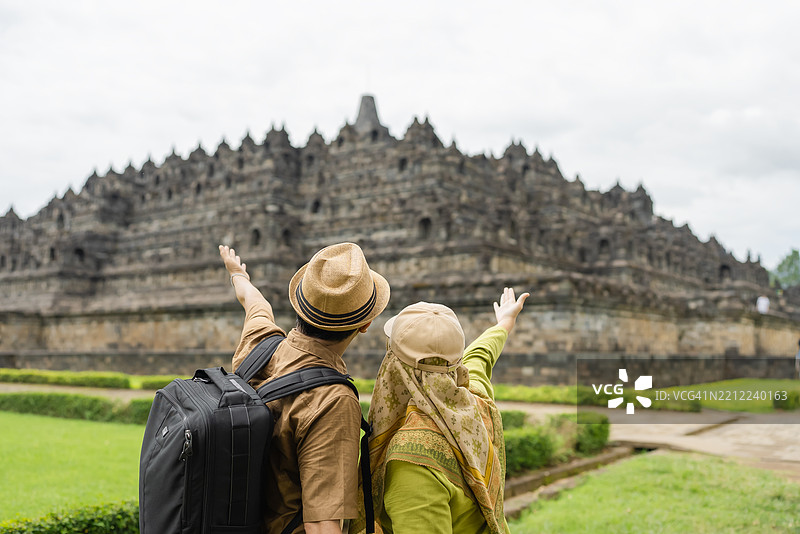两对情侣在游览婆罗浮屠寺时，举起手臂欢呼的背影镜头图片素材